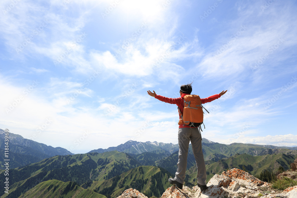 cheering young woman backpacker open arms on mountain peak cliff cheering young woman backpacker open arms on mountain peak cliff