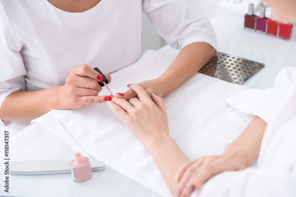 Skillful beautician doing manicure for girl