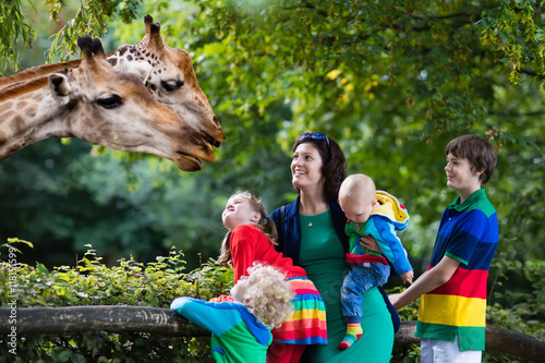 Mother and kids feeding giraffe at the zoo