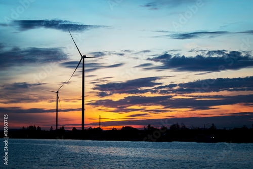 Silhouette of wind turbine at river background