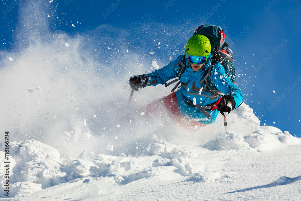 Freeride skier on piste running downhill