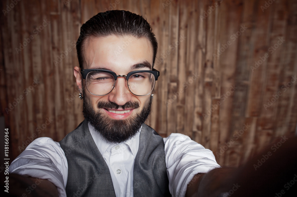 Funny stylish young guy doing selfie on a wooden background Funny stylish young guy doing selfie on a wooden background