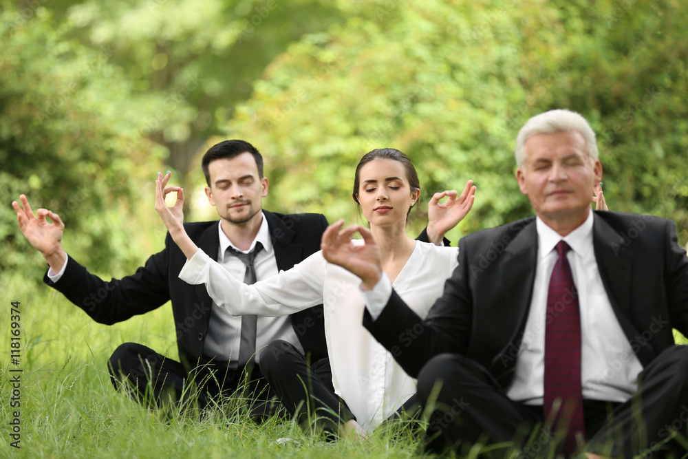 Business people relaxing in meditation pose in park Business people relaxing in meditation pose in park