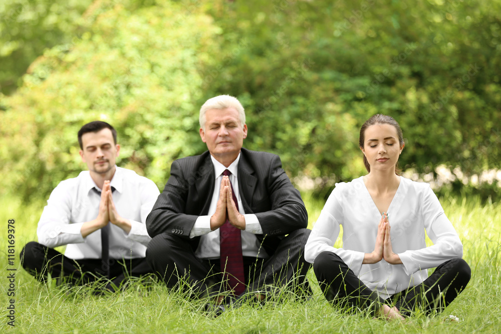 Business people relaxing in meditation pose in park Business people relaxing in meditation pose in park