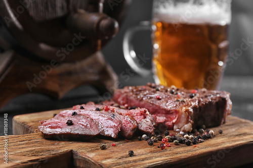 Tasty grilled steak with beer on cutting board