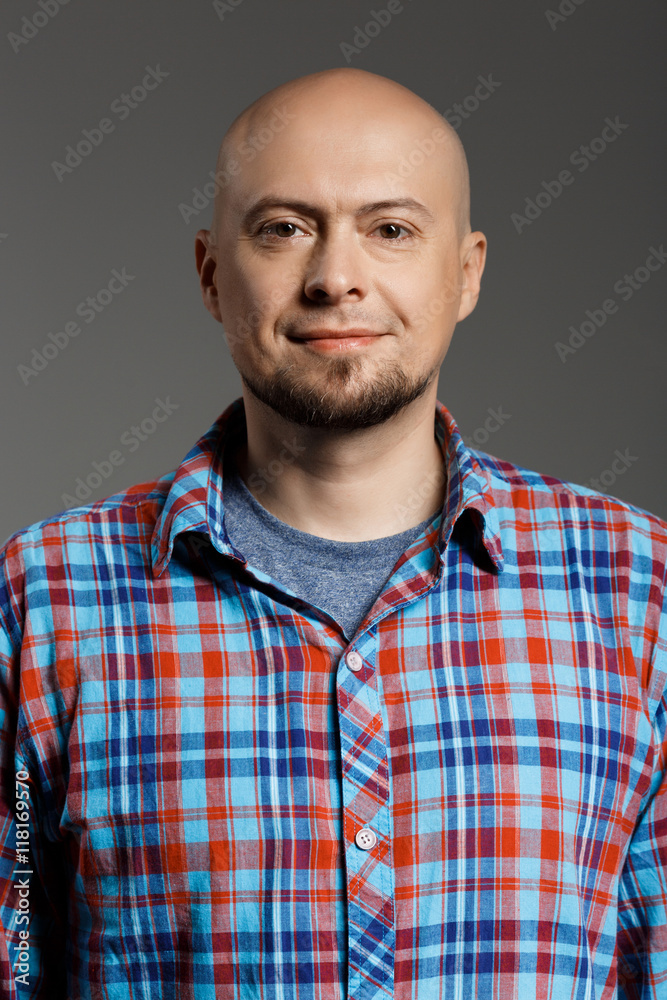 Portrait of cheerful handsome middle-aged man in plaid shirt looking at camera smiling over grey background. Portrait of cheerful handsome middle-aged man in plaid shirt looking at camera smiling over grey background.