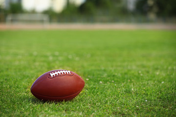 American football ball on a green grass