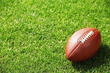 American football ball on a green grass