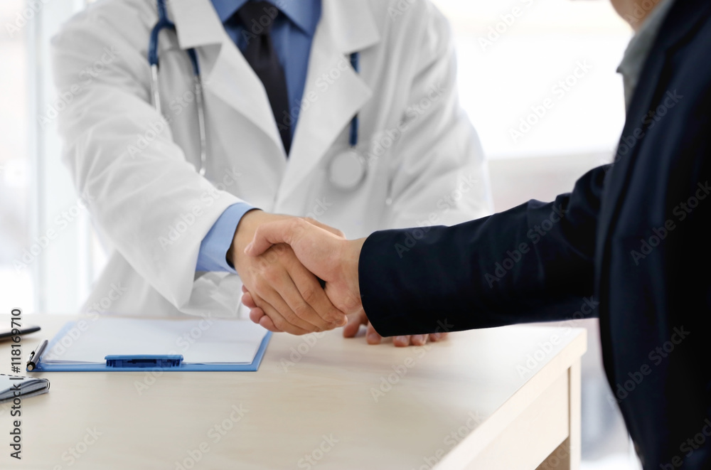 Doctor hand shaking with man at hospital