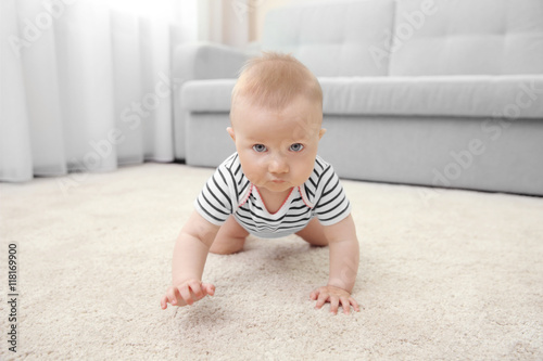 Adorable little baby crawling on light carpet