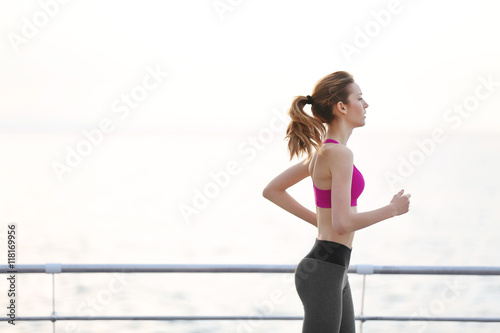 Young woman running on pier