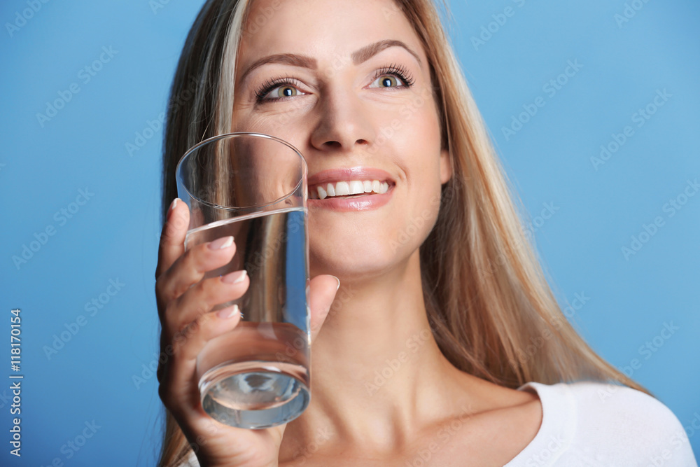 Beautiful girl drinking water on blue background