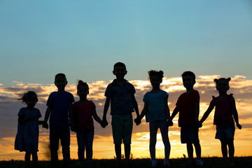 Happy kids silhouettes on sunset background