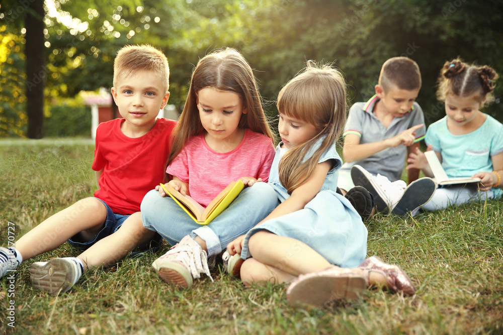 Group of happy kids reading books in park Group of happy kids reading books in park