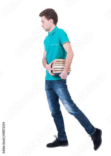 side view of going  man carries a stack of books. walking young guy . Rear view people collection.  backside view of person.  Isolated over white background. Curly kid in a turquoise jacket goes to © ghoststone