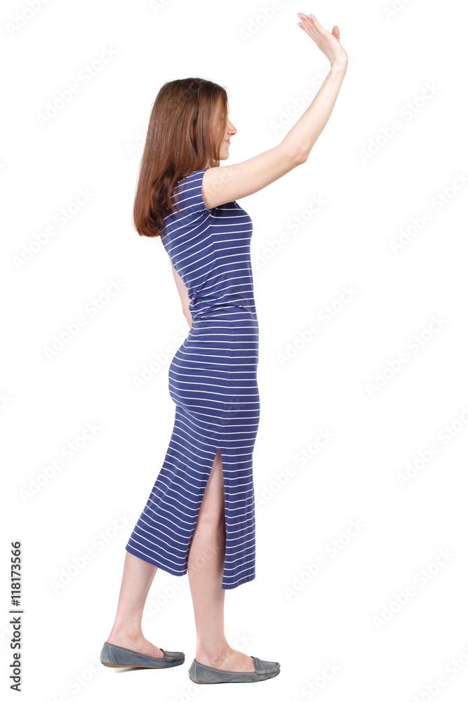 Side view of beautiful woman welcomes. Young teenager girl in jeans hand  waving from. Rear view people collection. backside view of person. Isolated  over white background. The brunette in a blue Stock-foto