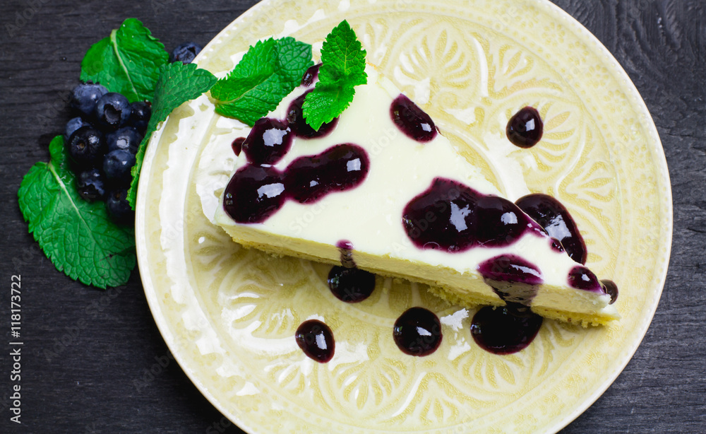 Fototapeta premium Piece of cheesecake on a black wooden background 