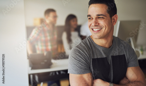 Smiling athletic man in office with co-workers