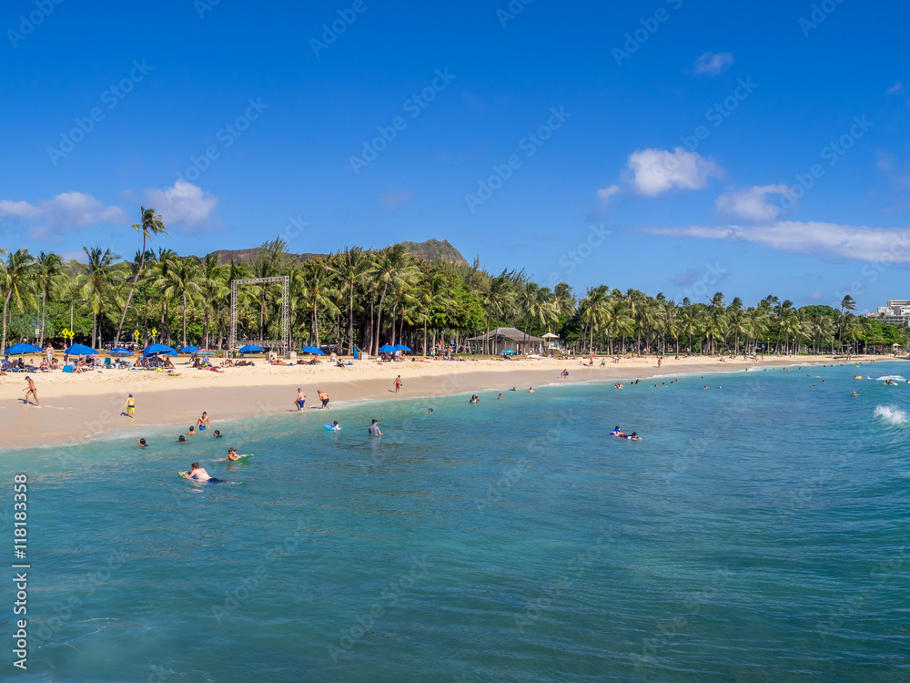 Obraz premium Sun lovers on Waikiki beach in Honolulu, Usa. Waikiki beach is neighborhood of Honolulu, best known for white sand and surfing.