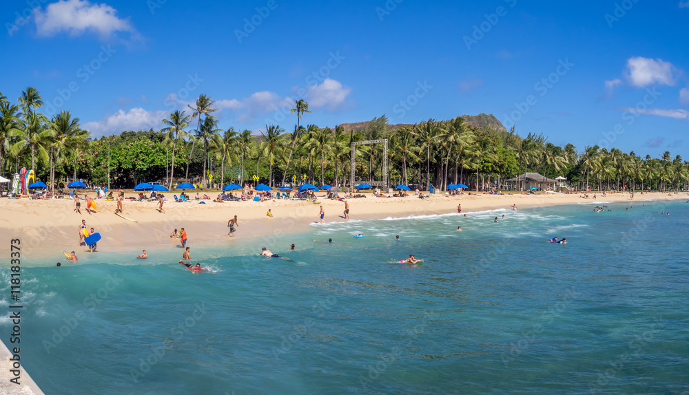 Sun lovers on Waikiki beach in Honolulu, Usa. Waikiki beach is neighborhood of Honolulu, best known for white sand and surfing.