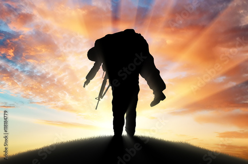 Soldier carries a wounded soldier at sunset