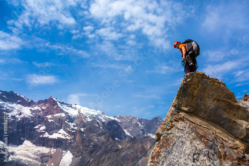 Alpine Climber staying on rocky Cliff