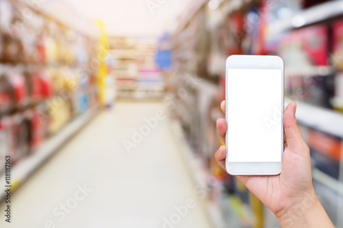 Female hand holding mobile smartphone on supermarket aisle backg
