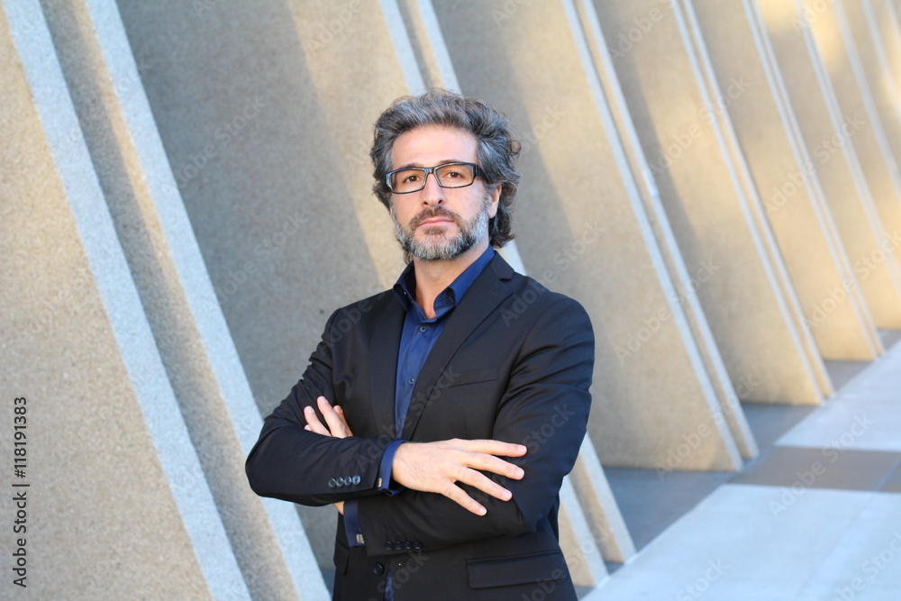 Confident mature businessman posing outside modern office building background with copy space Confident mature businessman posing outside modern office building background with copy space