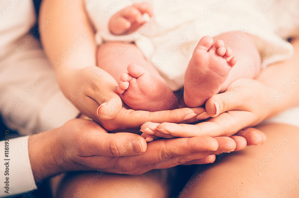 mom and dad hold the baby's legs mom and dad hold the baby's legs