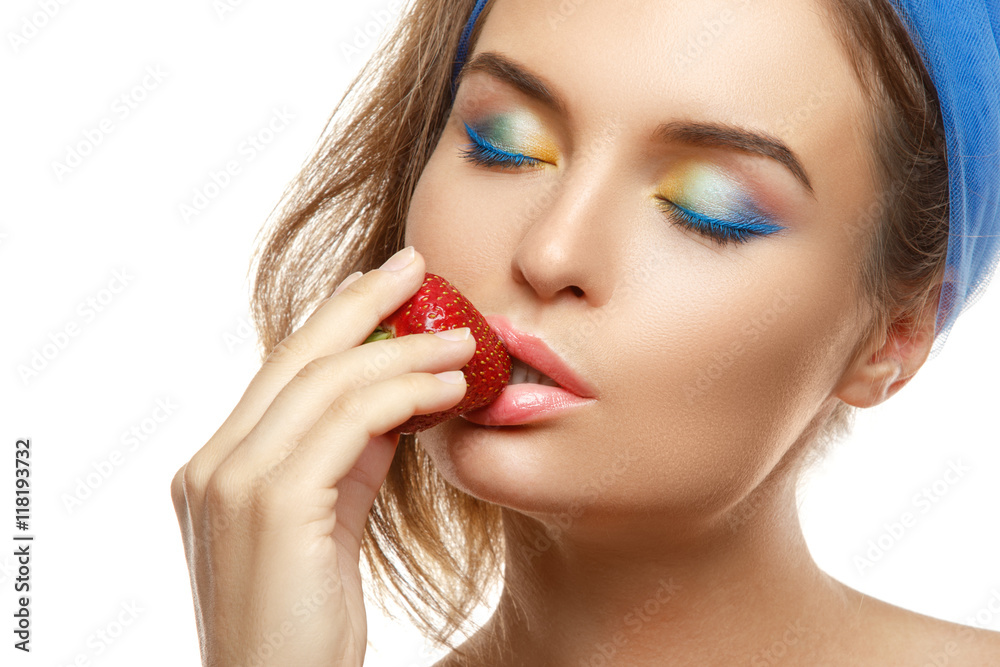 Woman with colorful makeup is eating strawberry