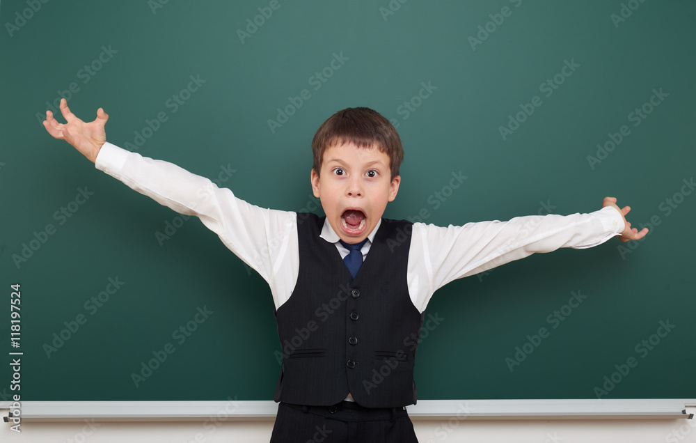 school student boy posing at the clean blackboard and open arms, grimacing and emotions, dressed in a black suit, education concept, studio photo school student boy posing at the clean blackboard and open arms, grimacing and emotions, dressed in a black suit, education concept, studio photo
