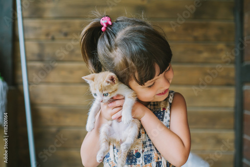 cheerful little girl holding a cat in her arms