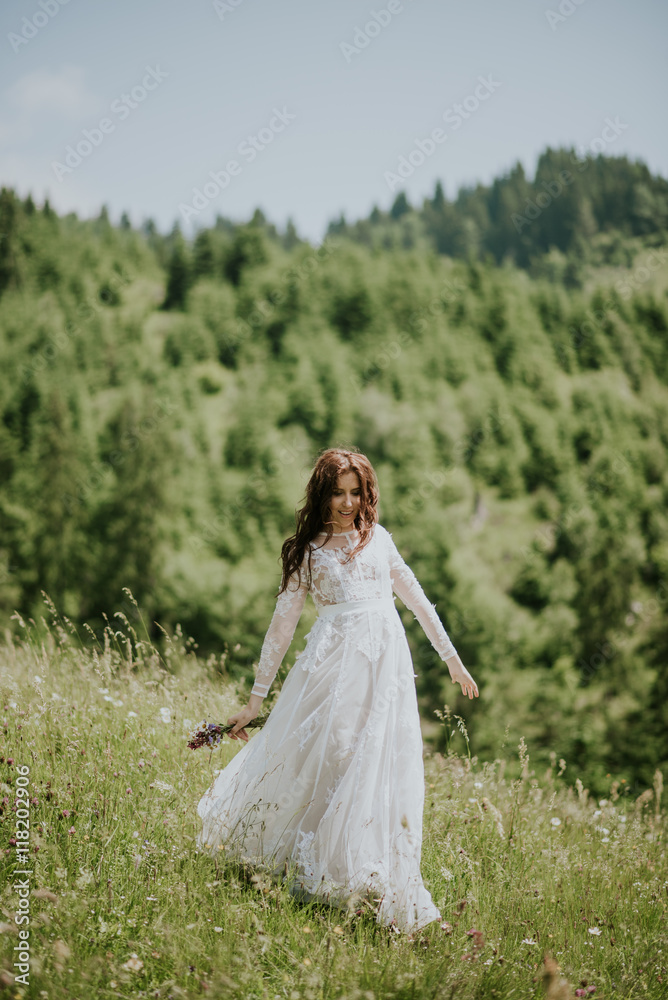 Vintage photography of a young hipster bride posing in wedding dress at sunset in the forest and mountains