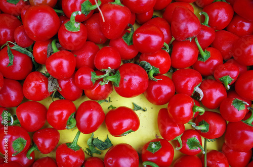 Red hot cherry peppers displayed on yellow background