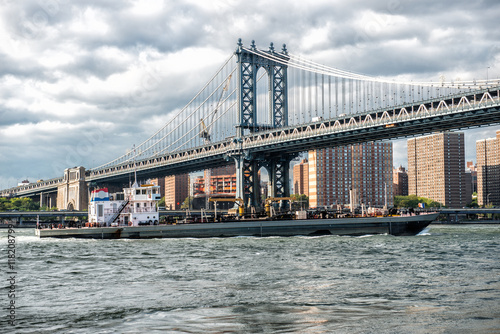Commercial cargo vessel ship at Eat River in New York City under Manhattan Bridge