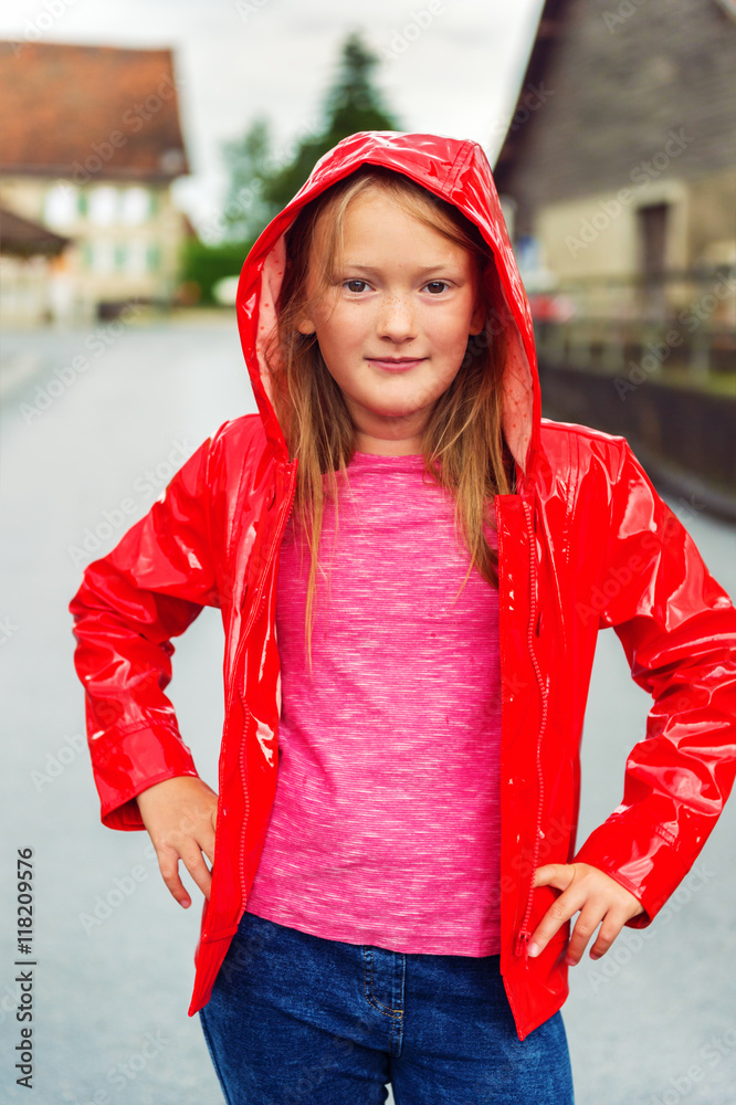 Vertical outdoor portrait of a cute little girl of 8-9 years old on a  cloudy day, wearing bright red rain jacket Stock Photo | Adobe Stock
