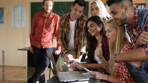 Students excited watching video using tablet computer and laptop university