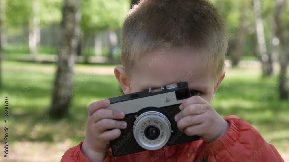 Close-up shot of cute little boy with retro camera in the park Close-up shot of cute little boy with retro camera in the park