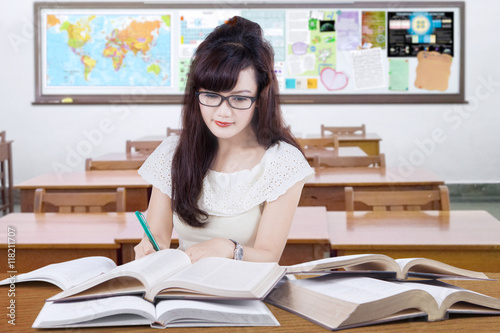 Pretty student learns with books in class