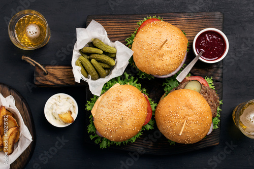 Different burger with pickles, ketchup, mayonnaise, fries and li