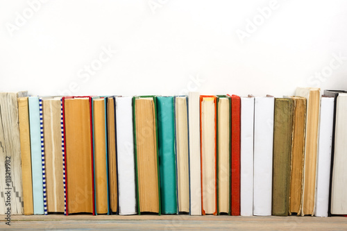 Books on grunge wooden table desk shelf in library. Back to school background with copy space for your ad text. Old hardback   no labels, blank spine