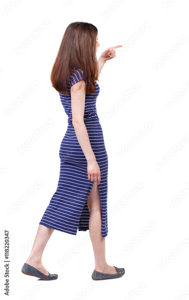 back view of pointing walking woman. going girl pointing. backside view of person. Rear view people collection. Isolated over white background. The brunette in a blue striped dress goes on the side back view of pointing walking woman. going girl pointing. backside view of person. Rear view people collection. Isolated over white background. The brunette in a blue striped dress goes on the side