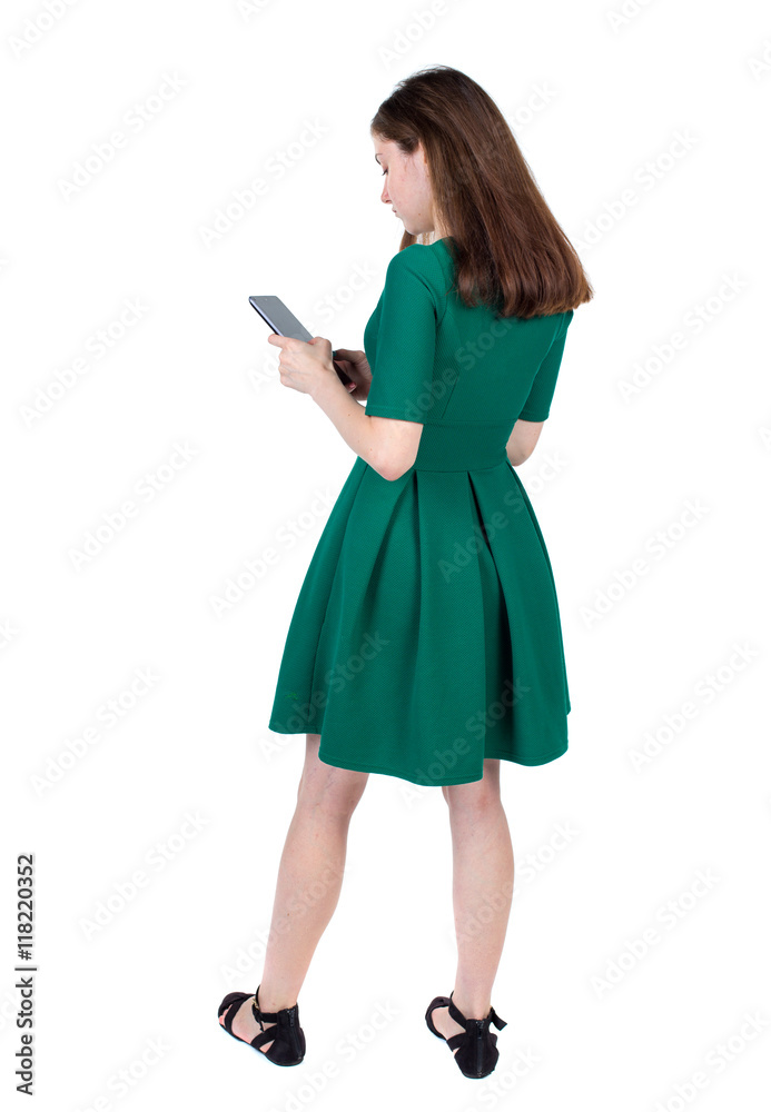 back view of standing young beautiful woman using a mobile phone or tablet computer. girl watching. Rear view people collection. backside view of person. Isolated over white background. Slim back view of standing young beautiful woman using a mobile phone or tablet computer. girl watching. Rear view people collection. backside view of person. Isolated over white background. Slim