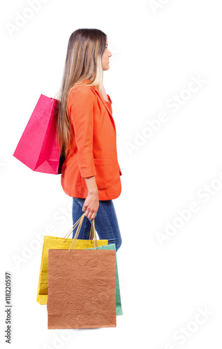 side view of going woman with shopping bags . beautiful girl in motion. backside view of person. Rear view people collection. Isolated over white background. girl in red coat is throwing his bag