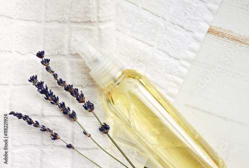 Spray bottle of oil, white towel, lavender dried flowers. Natural skincare and sun-protector. Empty space, top view.