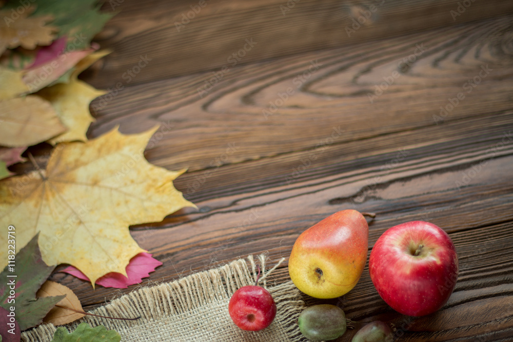 pear and red apples scattered with  fallen leaves on wooden table with sackcloth.