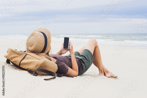 Young woman using smart phone on a beach. Relaxation concept
