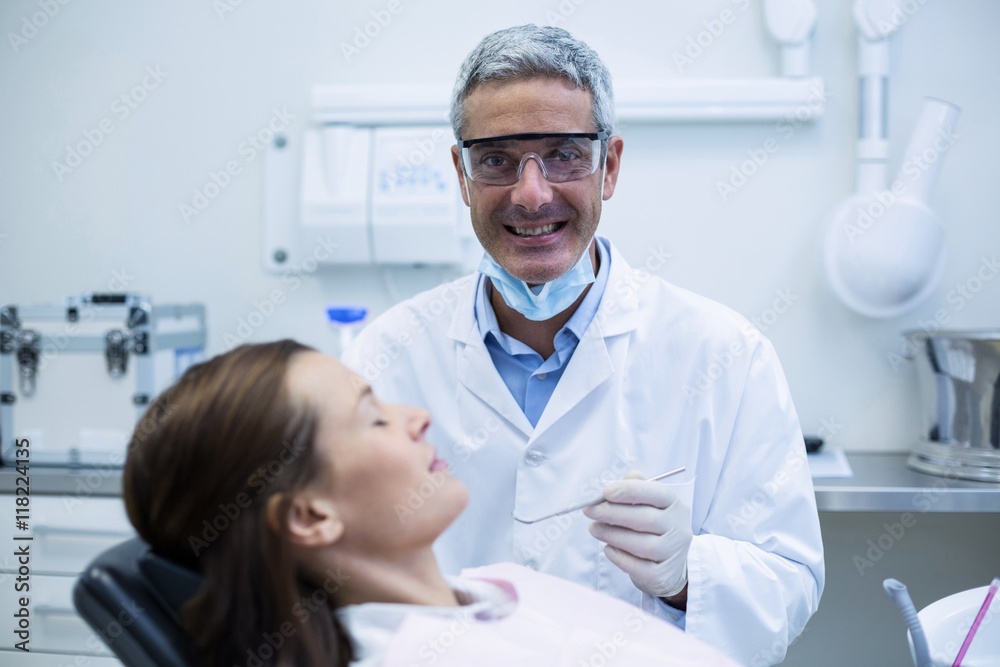 Smiling Dentist examining a patient with tools Smiling Dentist examining a patient with tools