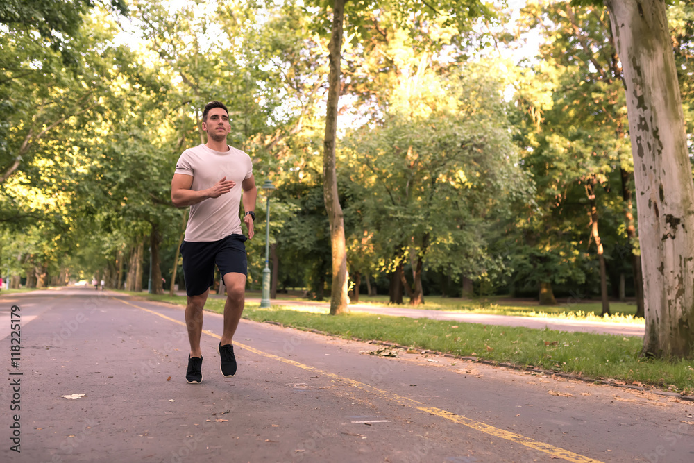 A handsome young man jogging in a park	