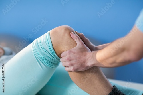 Male physiotherapist giving knee massage to female patient photo